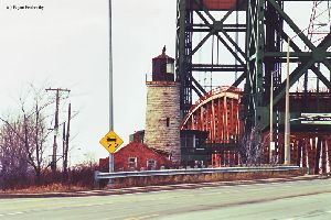 The light tower partially blocked by the bridge.